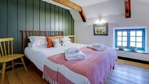 Een slaapkamer met een houten bed, een houten stoel, een raam met uitzicht en een schilderij aan de muur.