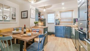 A modern kitchen with wooden flooring, a dining table with chairs, and built-in cabinets.