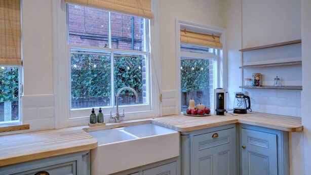 A kitchen with a large sink, wooden countertops, and a window with a view of greenery. - Amazing coastal house, with beautiful sea views (Cromer)