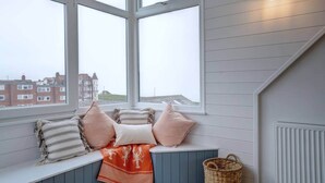A cozy room with a large window, a view of buildings, and a radiator. - Amazing coastal house, with beautiful sea views (Cromer)