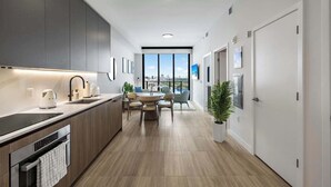 A modern kitchen with a dining area, large windows, and a view of the city.