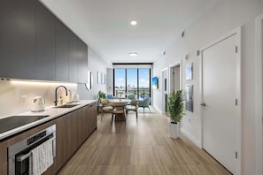 A modern kitchen with a dining area, large windows, and a view of the city. - Ocean Terrace 1BR: Pool, Near Miami Stadium (Miami Beach)