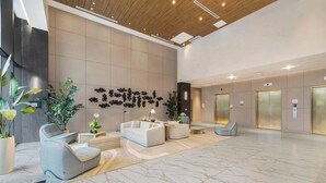 A spacious lobby with a marble floor, modern seating, and a wall with abstract art.