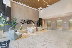 A modern lobby with marble flooring, seating areas, and a wall with abstract art. - Ocean Terrace 1BR: Pool, Near Miami Stadium (Miami Beach)