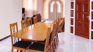 A dining area with a wooden table and chairs, a television, and a sofa. - Paramaribo Villa for 8 People, 4 Bedrooms, Full Air Conditioning, Near the Mall, Including Housekeeping Service! (Paramaribo)