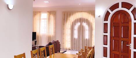 Un comedor con una mesa y sillas de madera, una televisión y un sofá.