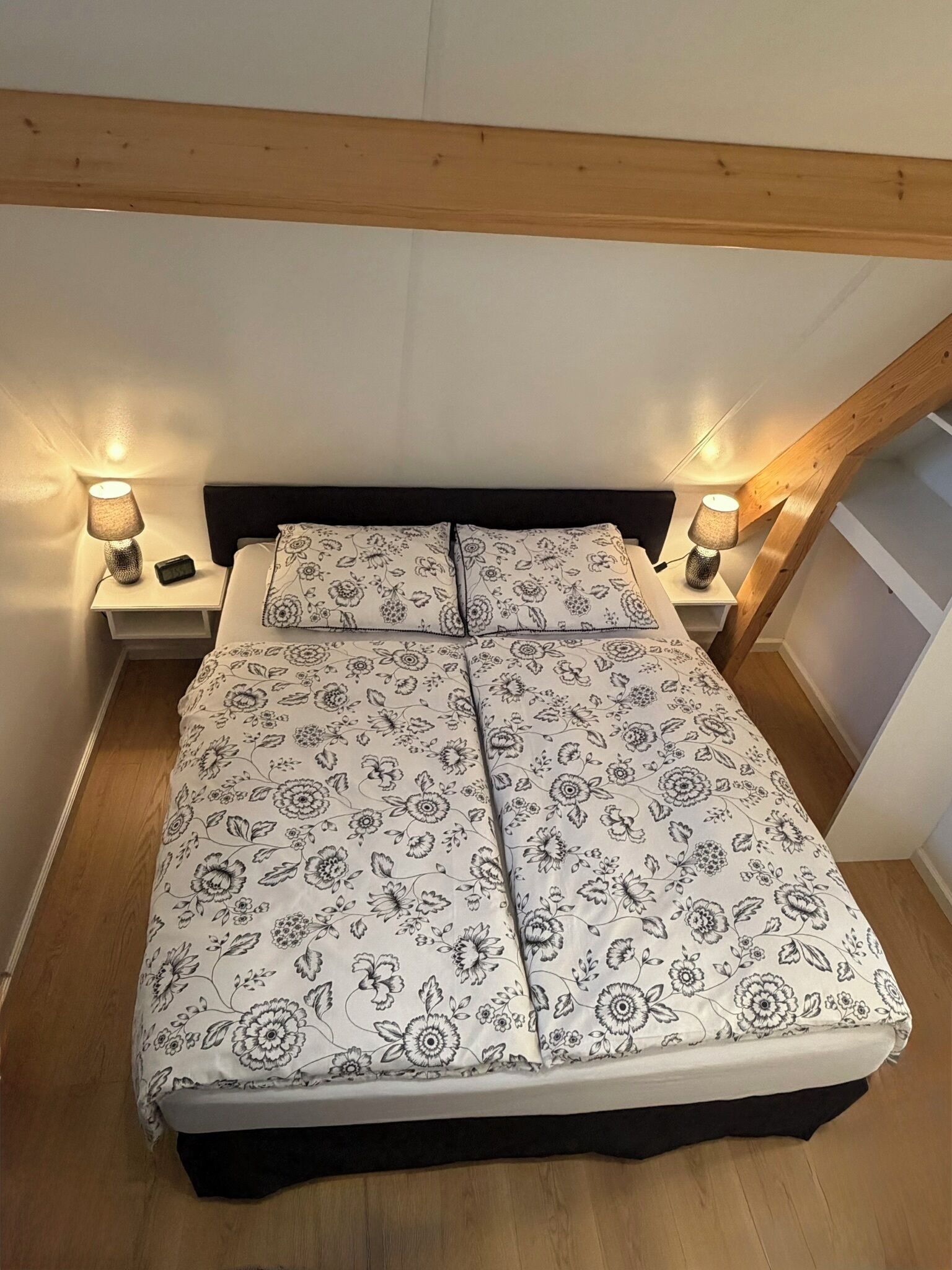 A bedroom with a bed, two bedside tables, and two lamps.