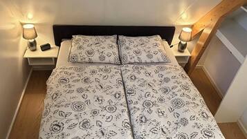 A bedroom with a bed, two bedside tables, and two lamps.