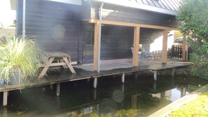 Ein Haus mit einem Steg, der ins Wasser ragt, einer überdachten Terrasse und einer Garage.
