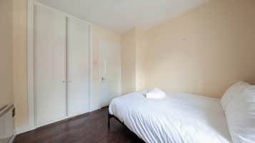 A bedroom with a bed, a wardrobe, and a door.