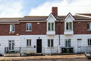A two-story brick house with white trim, a black front door, and a small front garden.