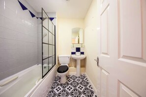 A bathroom with a bathtub, toilet, and sink.