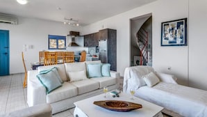 Un salon moderne comprenant un canapé, une table basse et un coin repas avec des chaises.