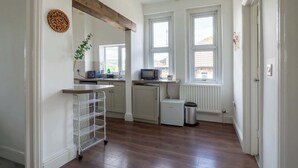 A kitchen with a white fridge, a microwave, a sink, and a window. - Refurbished Modern 2BD Flat, Lower Oldfield Park (Bath and North East Somerset)