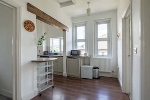 A kitchen with a white fridge, a microwave, a sink, and a window. - Refurbished Modern 2BD Flat, Lower Oldfield Park (Bath and North East Somerset)
