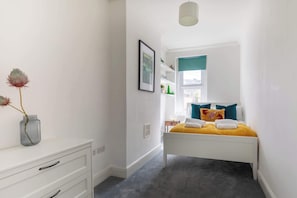 A bedroom with a bed, bedside table, and a vase with flowers. - Refurbished Modern 2BD Flat, Lower Oldfield Park (Bath and North East Somerset)