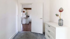 A hallway with a white door leading to a kitchen area. - Refurbished Modern 2BD Flat, Lower Oldfield Park (Bath and North East Somerset)