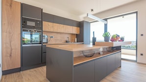 Een moderne keuken met een groot eiland, inbouwapparatuur en uitzicht op de omgeving.