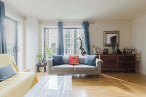 Un salon avec un canapé, une table basse, un meuble et une fenêtre avec des rideaux.