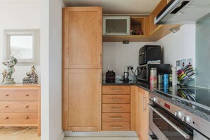 A compact kitchen with wooden cabinets, a microwave, and a built-in oven.