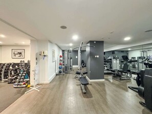 A gym with weight machines, treadmills, and a bench.