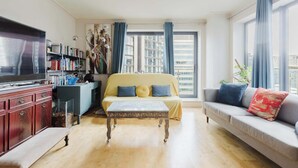 Ein modernes Wohnzimmer mit einer Couch, einem Couchtisch, einem Fernseher und einem Bücherregal.