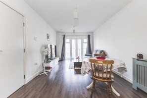 Een kamer met een eettafel, een stoel, een radiator en een raam met gordijnen.