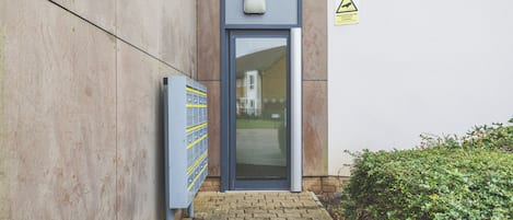 A building entrance with a blue door, a security keypad, and a warning sign.