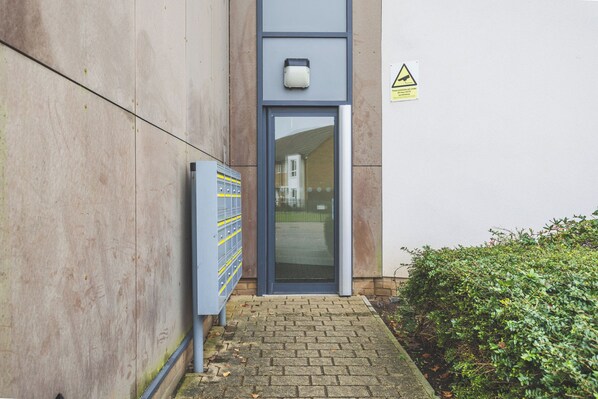 A building entrance with a blue door, a security keypad, and a warning sign.