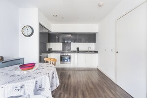 Een moderne keuken met witte kastjes, een inbouwoven en een koffiezetapparaat.