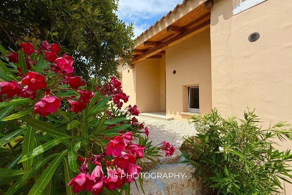 A building with a beige exterior, a wooden pergola, and a gravel pathway leading to a door. - Modern new Villa with 4 bedrooms and sea views. With private Pool (2026) (Sassari)