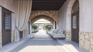 A covered outdoor seating area with stone walls, a sofa, and a patterned rug. - Enliven Lifestyle Hotel Nicosia (Nicosia)