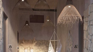 A room with a hanging chair, stone wall, and three hanging light fixtures. - Enliven Lifestyle Hotel Nicosia (Nicosia)