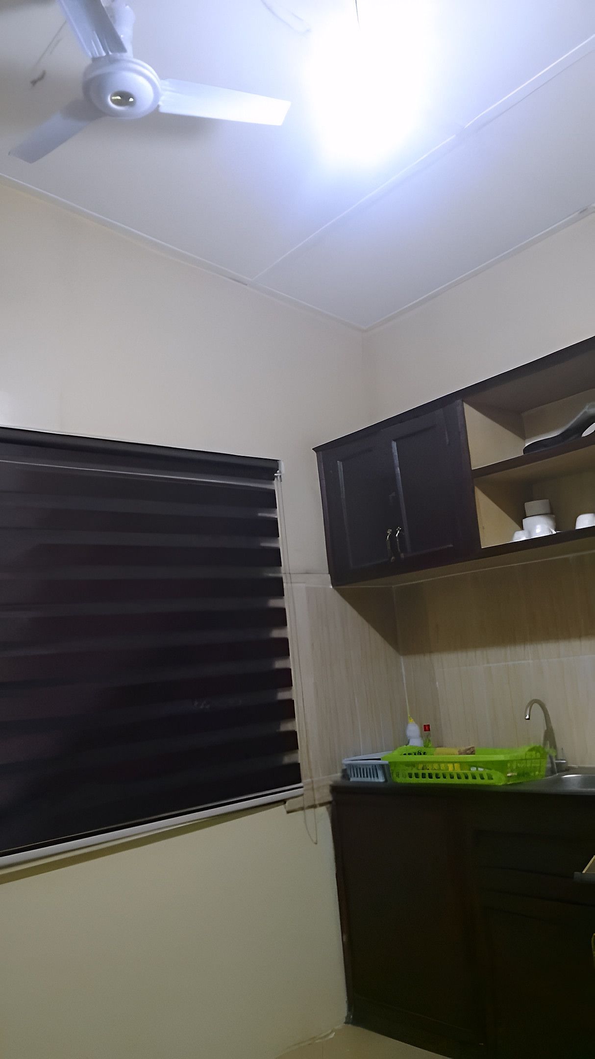 A kitchen with a window, a ceiling fan, and a sink area.