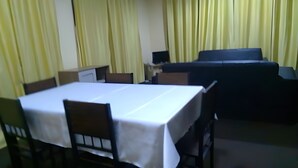 A dining area with a table and chairs, a sofa, and curtains. - Accra City Guest House (Accra North)