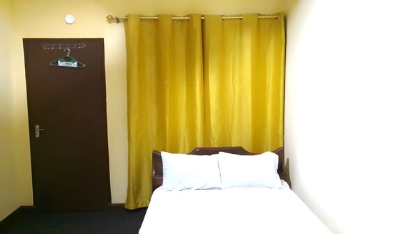 A room with a bed, a door, and curtains.