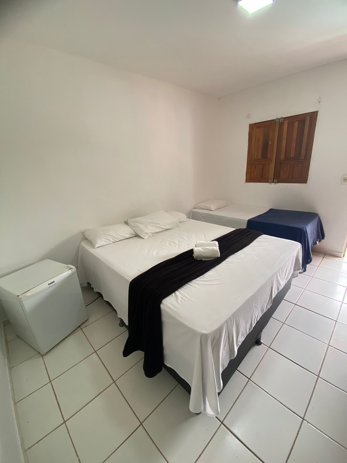 A room with a large bed, a smaller bed, a heater, and a wardrobe.