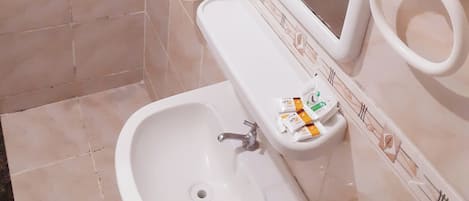 Un baño con lavamanos, espejo, inodoro y dispensador de jabón.