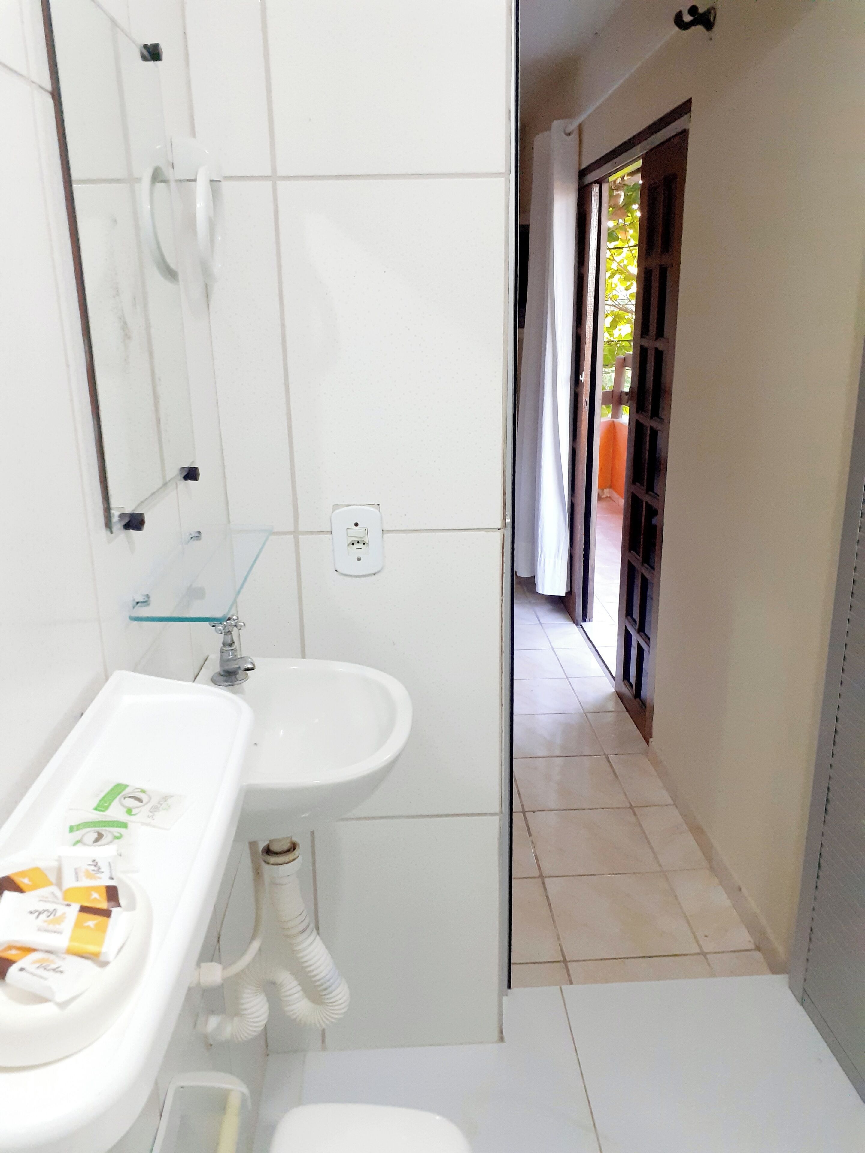 A bathroom with a white sink, mirror, and toilet. There is a glass shower enclosure and a tiled floor.