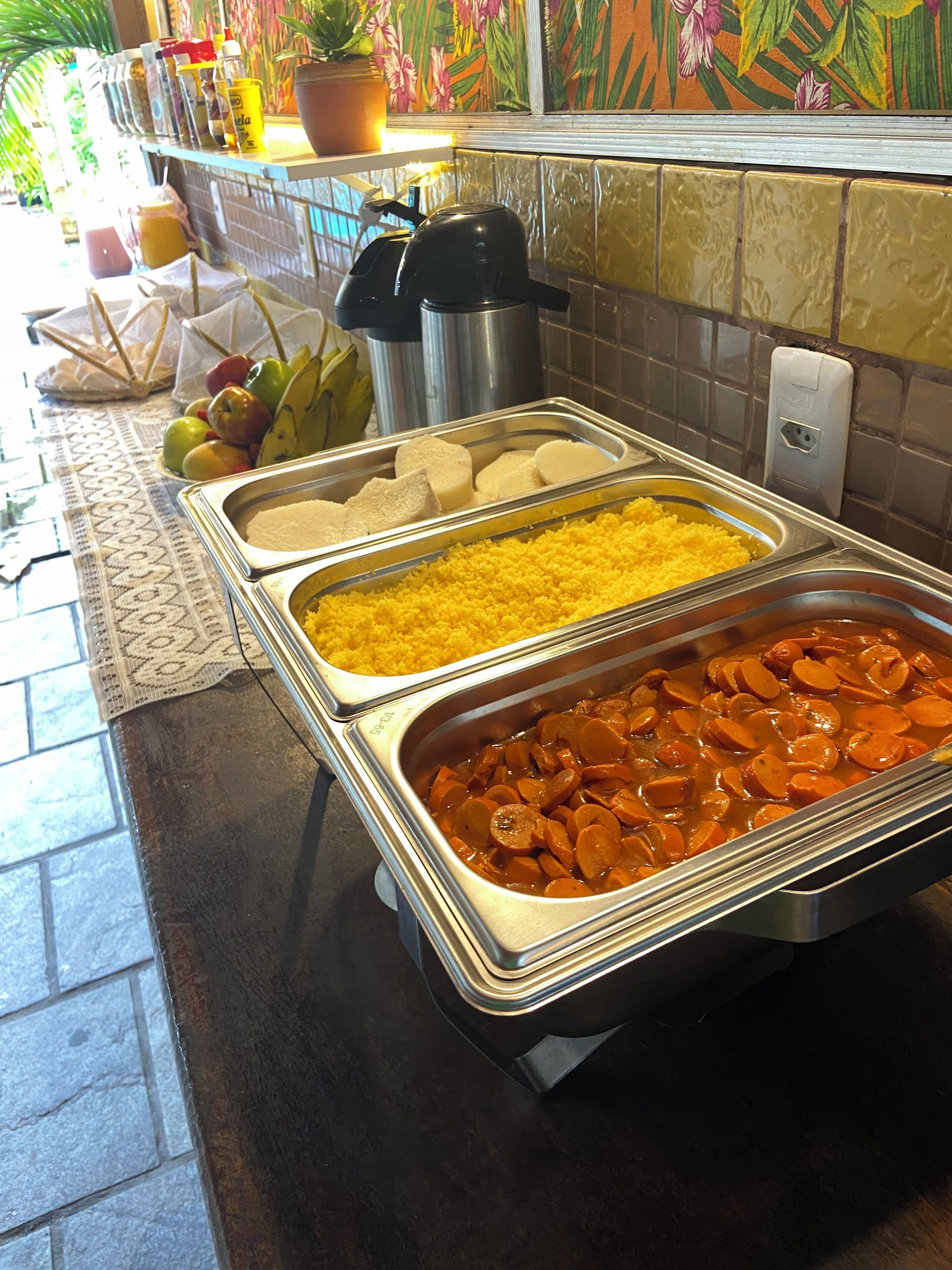 A buffet with various food items including rice, a meat dish, and fruits.