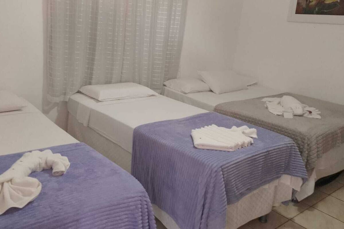 A hotel room with three beds, each with a different colored bedspread.