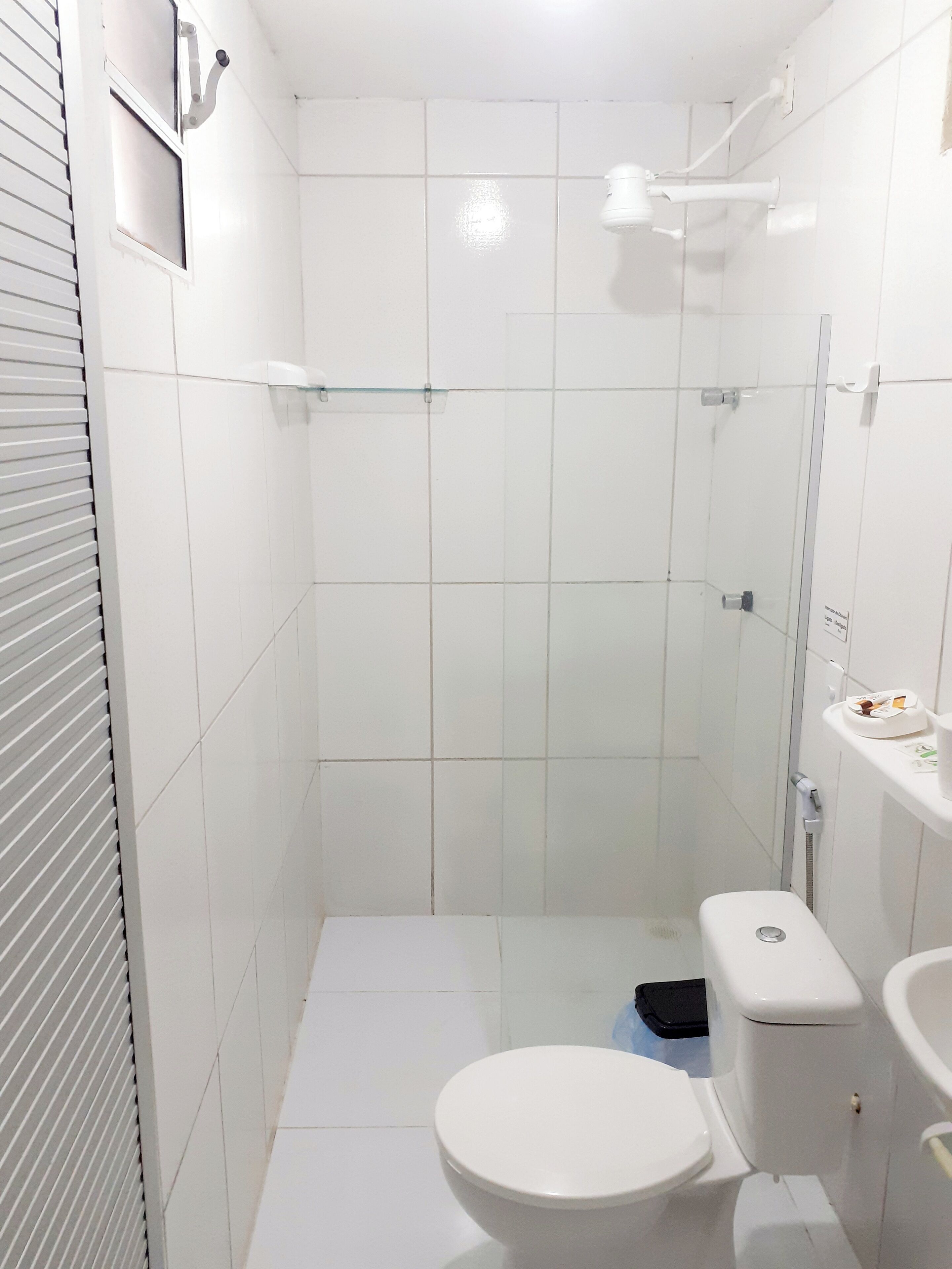 A small, white bathroom with a toilet, a shower, and a sink.