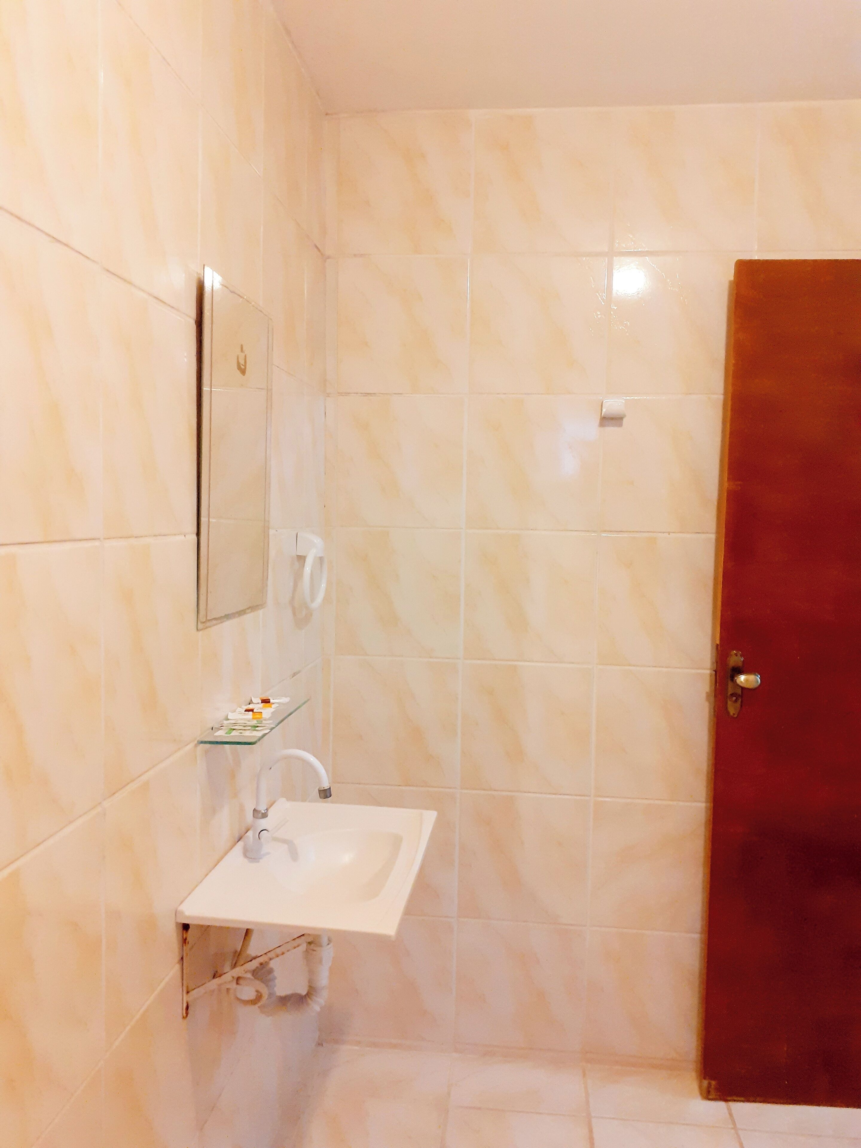 Een badkamer met een witte wastafel, een spiegel en een douchegedeelte.