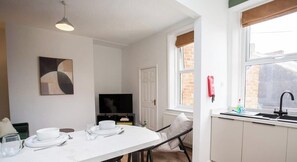 A modern kitchen with a dining area, a television, and a window with a view. - Vacant Nests | The Jackson | Wi-Fi | Parking (Tynemouth)