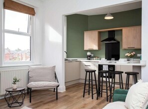 Une cuisine moderne avec des meubles en bois, une hotte noire et un coin bar avec des tabourets.