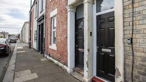 A row of terraced houses with brick facades, black doors, and a narrow sidewalk. - Vacant Nests | The Jackson | Wi-Fi | Parking (Tynemouth)