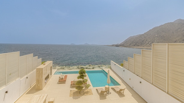 A rooftop pool area with a view of the sea and mountains.