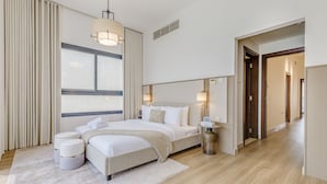 A modern hotel room with a large bed, bedside tables, a bedside lamp, a window with curtains, and a wooden floor.