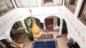 Ein Innenpool mit gefliestem Boden, umgeben von Bögen und einem Balkon mit Geländer.