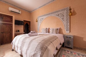 A bedroom with a bed, a nightstand, an air conditioning unit, and a wardrobe.